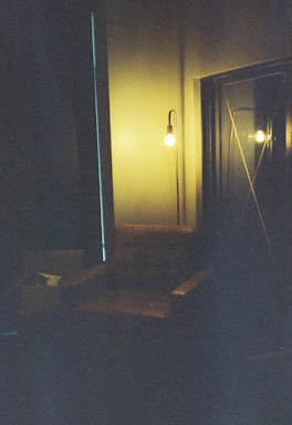 A cozy corner of the gallery with a vintage chair and a midcentury lamp casting warm light.