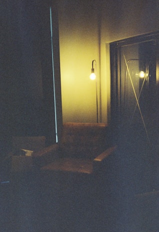 A dimly lit room with soft shadows casting over a vintage leather armchair and a flickering candle.