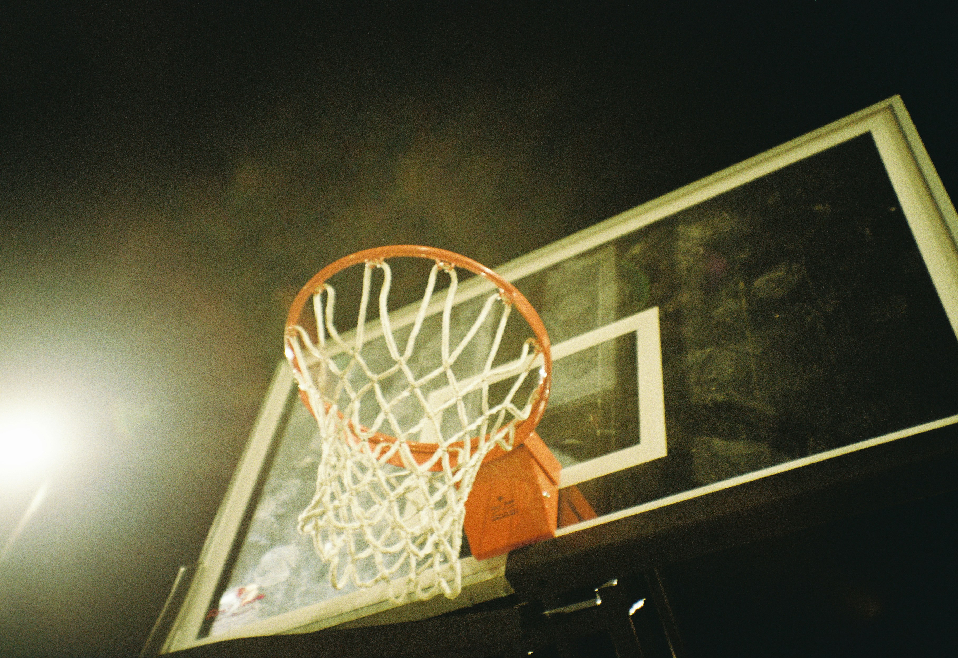 A basketball going through the net of a basketball court photo Free