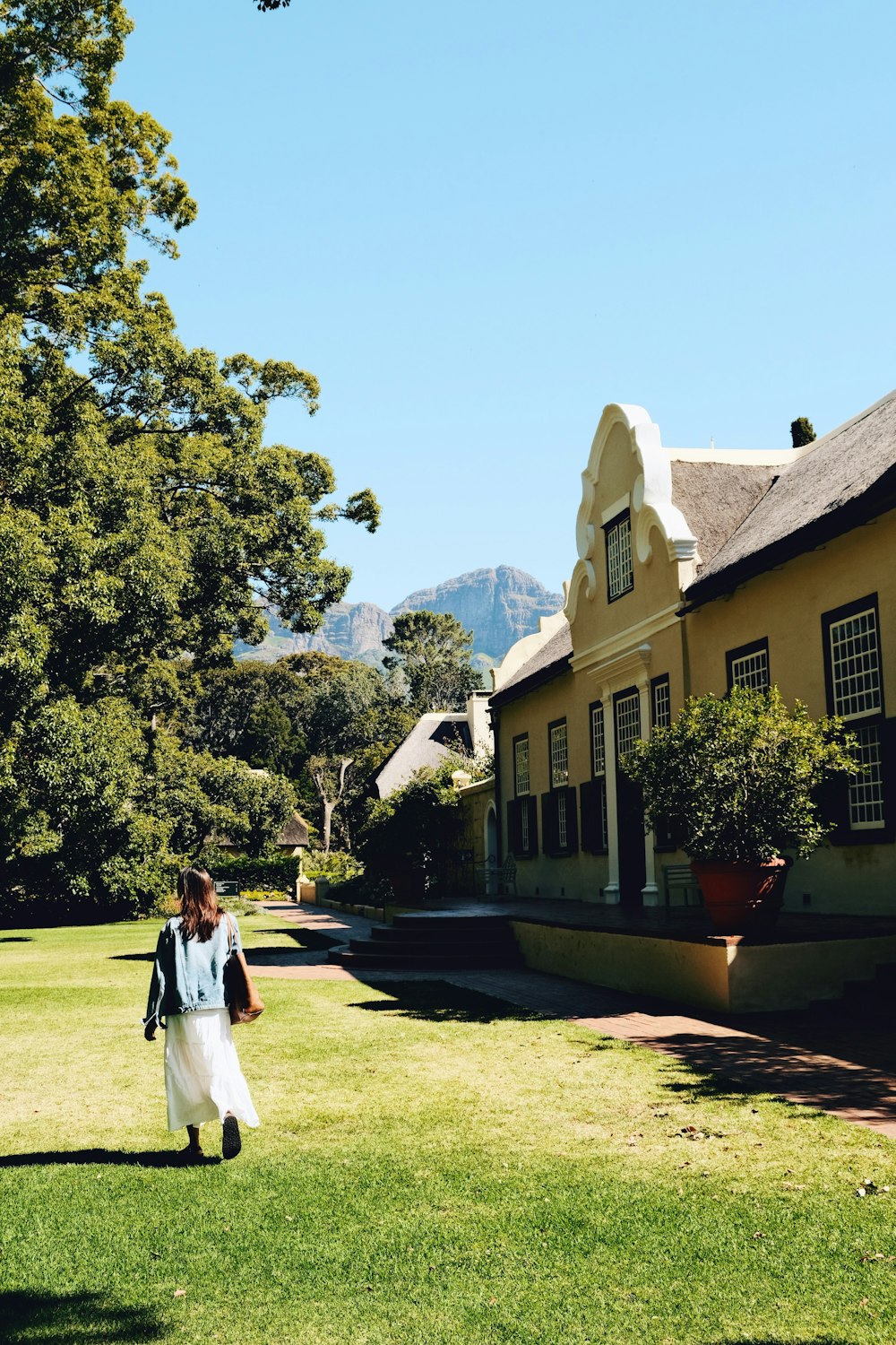 a woman in a white dress walking in front of a house