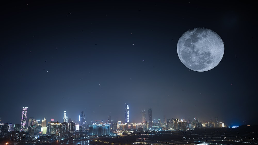 a full moon rising over a city at night