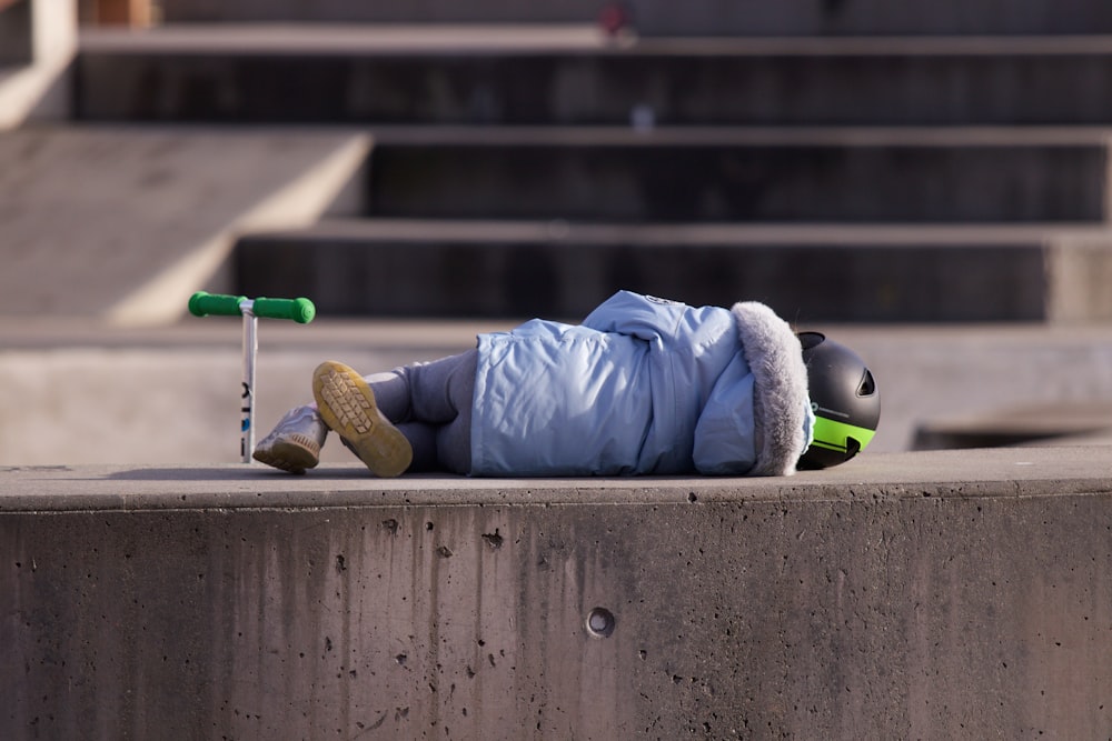 a little boy laying on top of a cement wall