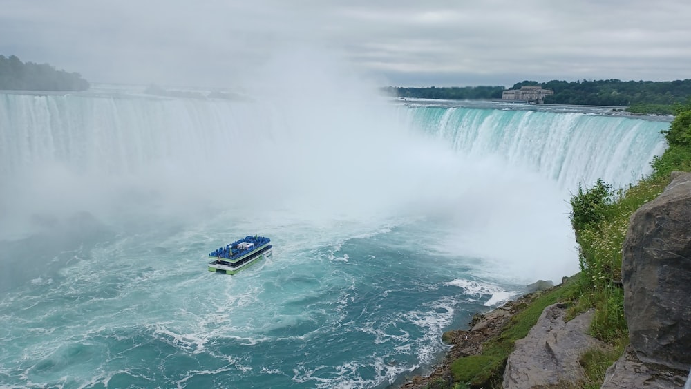 a boat in the water near a waterfall