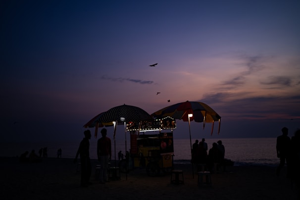 Evening scene showing the glowing mig+ açaí cart surrounded by happy customers at a local festival.