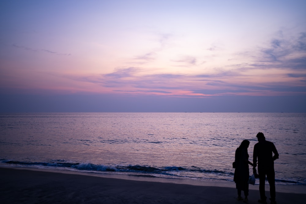 a couple of people standing on top of a beach