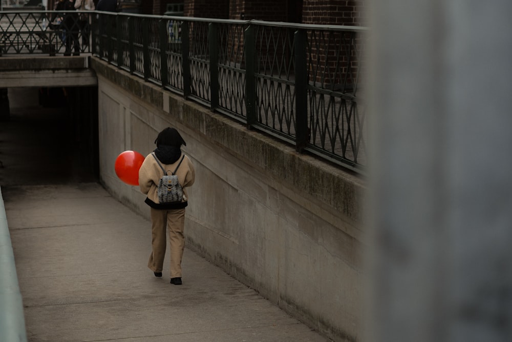 a person walking down a sidewalk with a red balloon