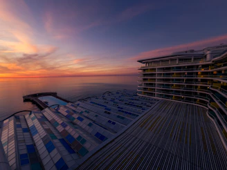 A modern apartment balcony overlooking the Mediterranean Sea at sunset.
