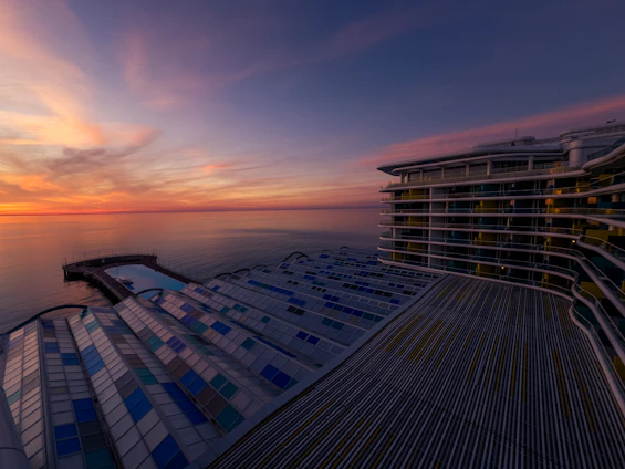 A panoramic view of Oceanavista’s sleek condominium building overlooking the sparkling blue ocean at sunset.
