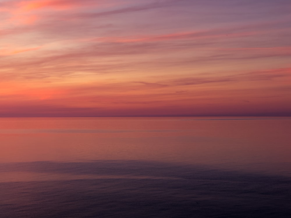 Un coucher de soleil sur l’océan avec un bateau dans l’eau