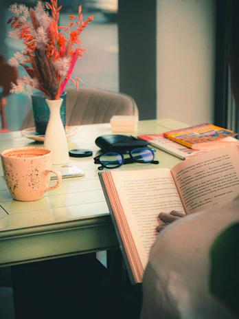 A calm setting featuring a tablet next to a cup of tea and reading glasses.