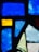 Several pieces of colorful stained glass are arranged in a pattern. The fragments include various shapes such as rectangles and triangles, with a mix of textures. The colors range from deep blue and bright yellow to shades of green and light blue.