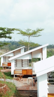 a couple of white buildings sitting on top of a lush green hillside
