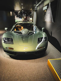 A sleek black and green luxury car showroom with a modern import process infographic on the wall.