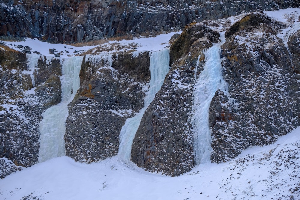 a large waterfall with snow on the ground