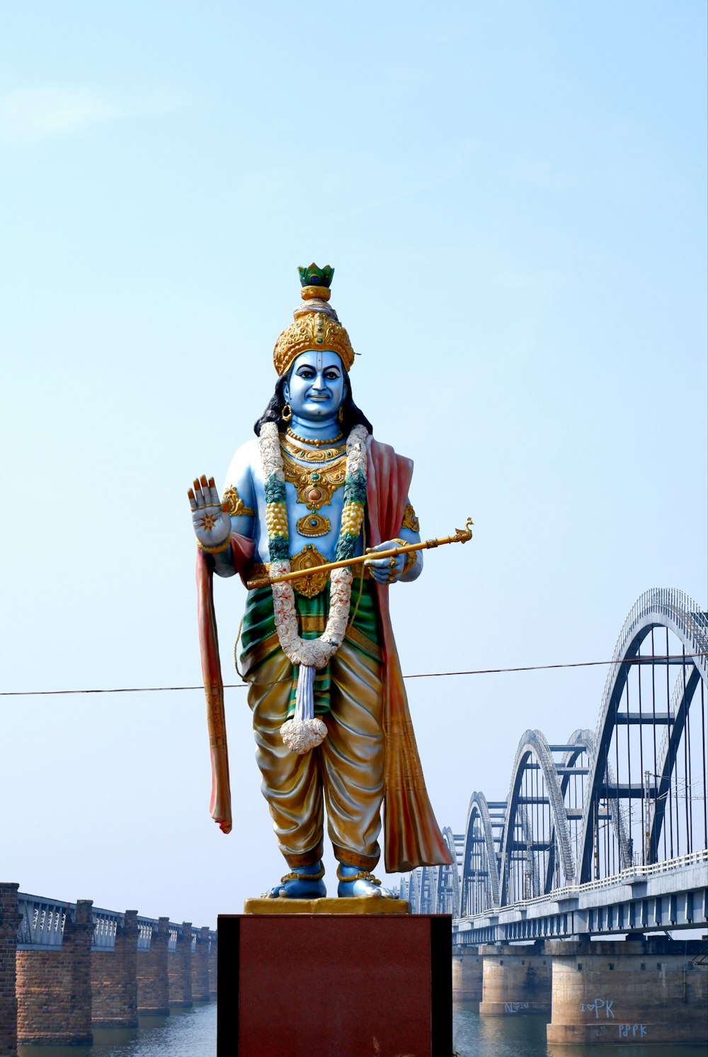 una statua di un uomo che tiene un bastone davanti a un ponte