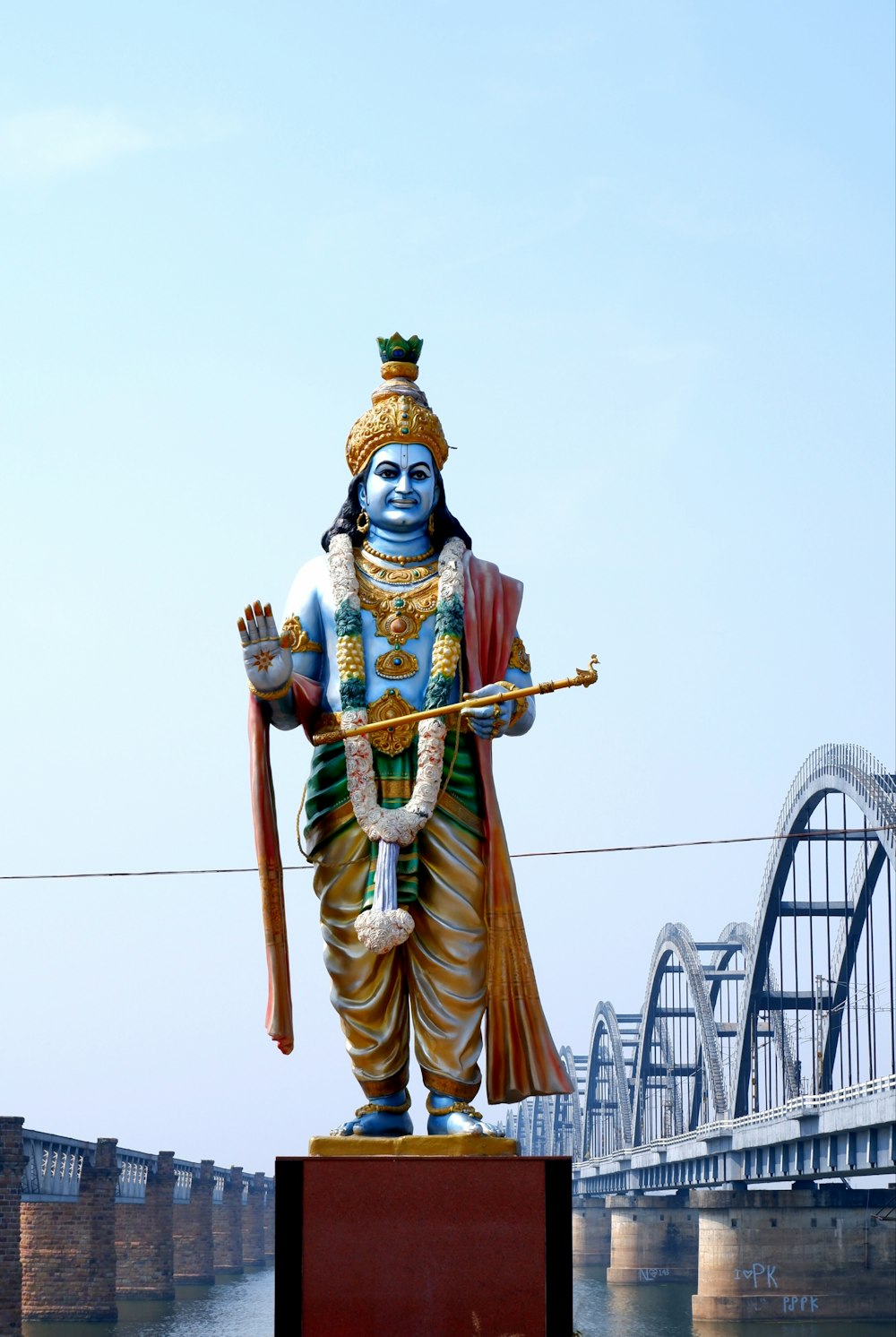 a statue of a man holding a stick in front of a bridge