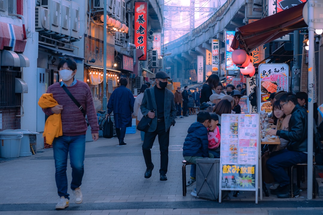 a group of people walking down a street next to tall buildings,