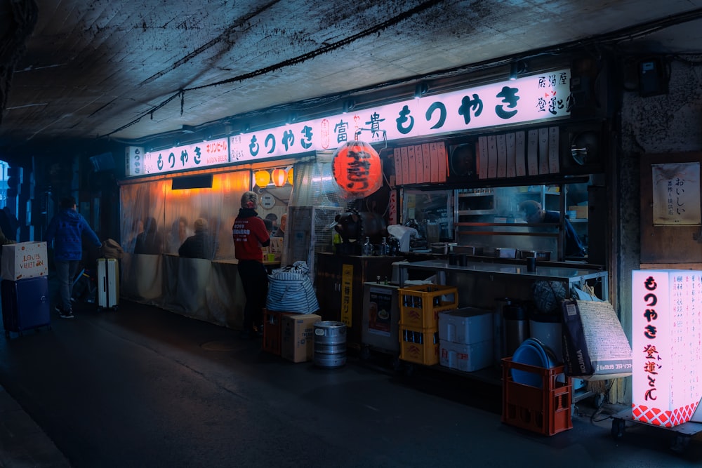 a man standing in front of a food stand at night