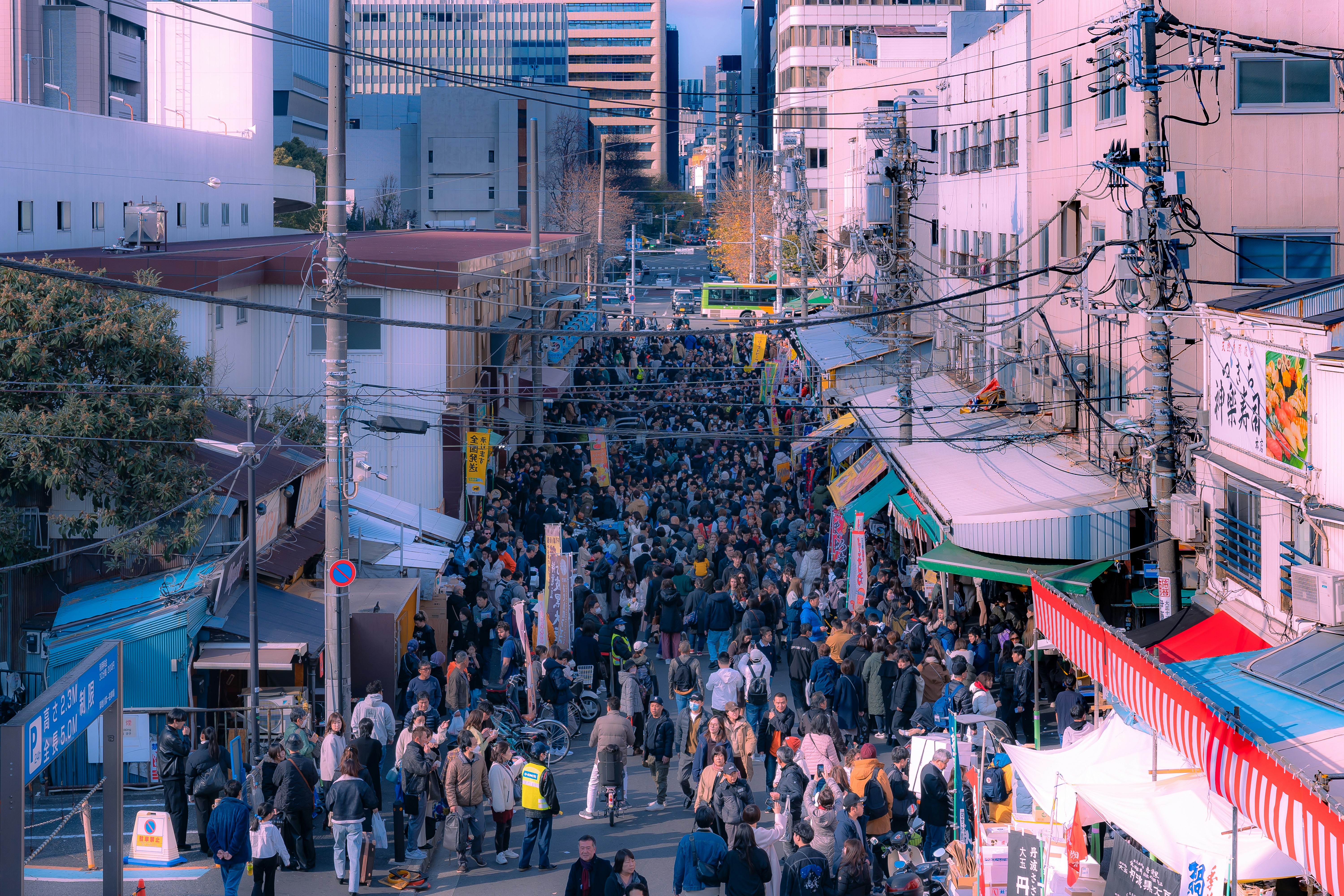 a crowd of people walking down a street next to tall buildings