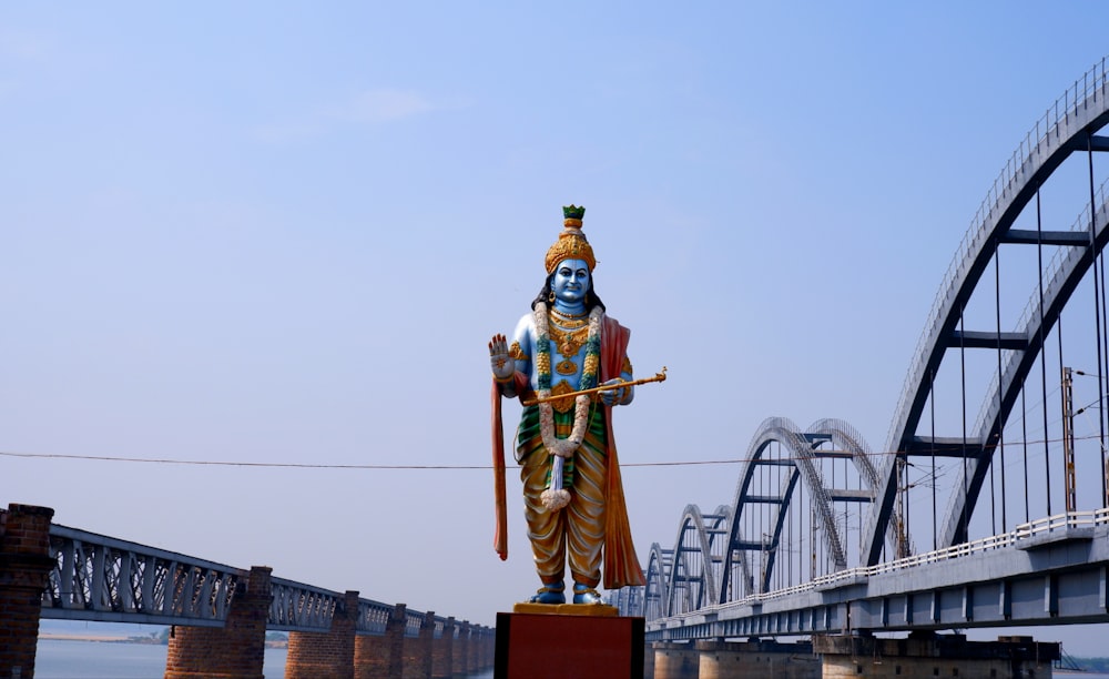 a statue of a hindu god stands in front of a bridge