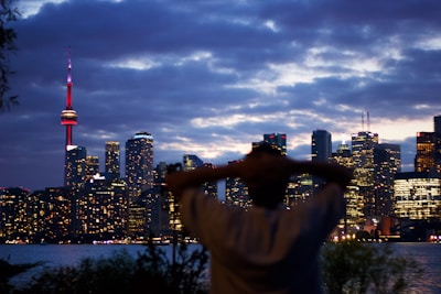 City skyline at dusk with a model wearing Atelier Lumina standing thoughtfully.