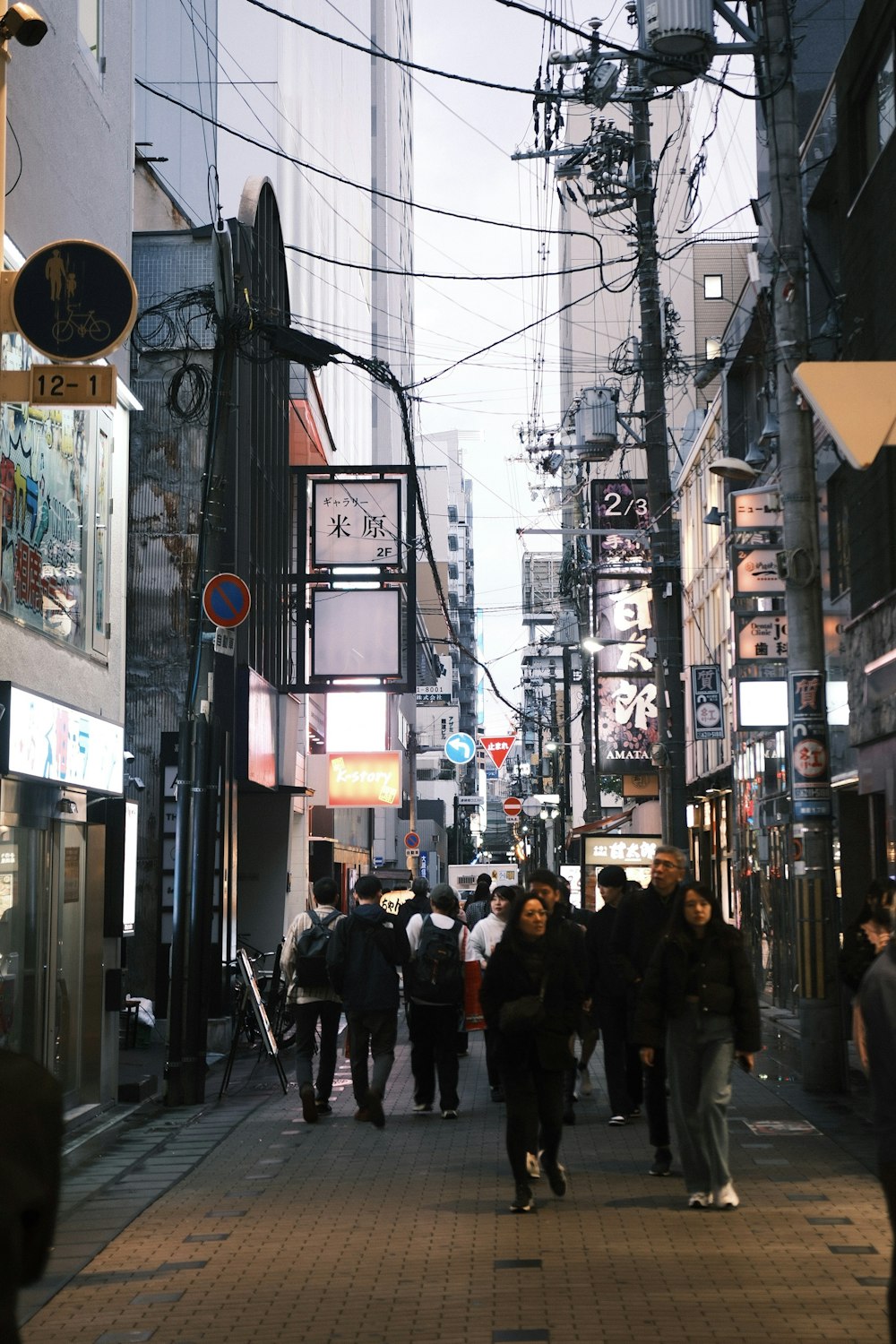 a group of people walking down a street next to tall buildings