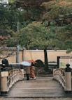 a couple of people walking across a bridge holding umbrellas