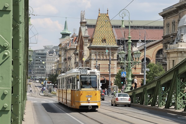 a yellow and white trolley traveling down a street next to tall buildings