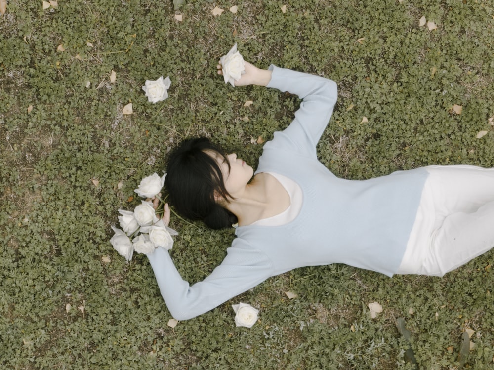 a woman laying in the grass with a bunch of flowers