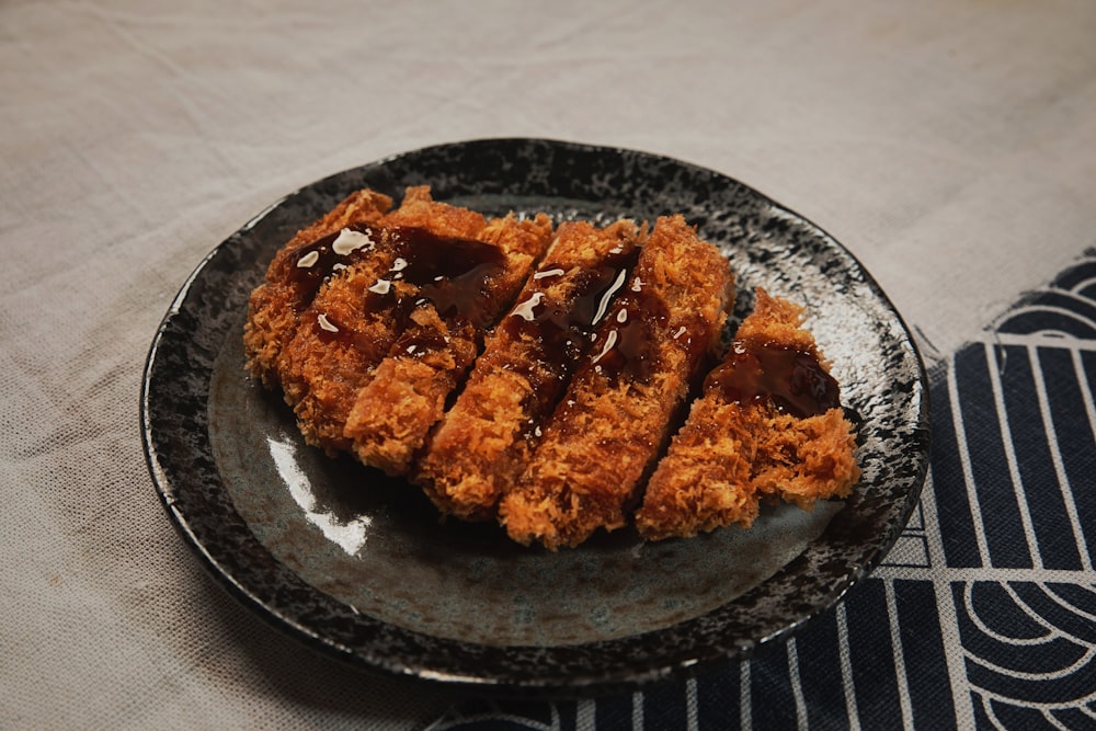 a black plate topped with fried food on top of a table