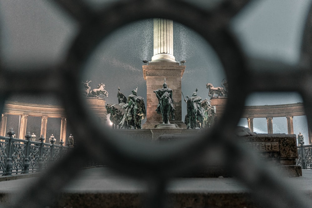 a view of a statue through a fence