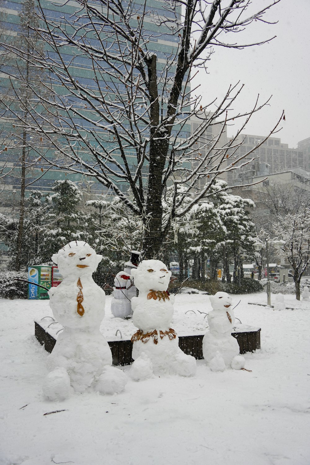a group of snowmen standing next to a tree