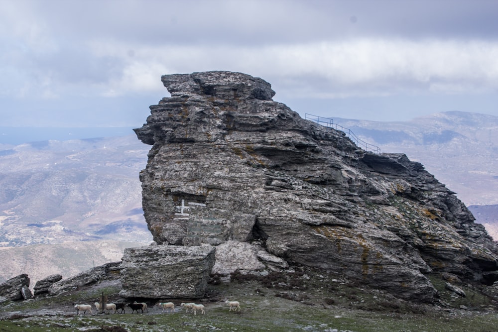 a rocky outcropping with sheep grazing on it