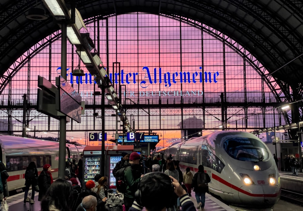 a group of people standing next to a train at a train station