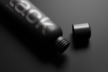 A sleek black matte bottle of Bright Citrus London Dry resting on a white surgical surface.