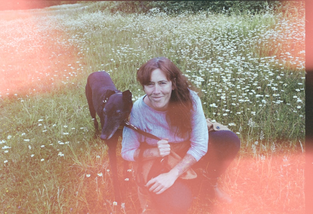 a woman sitting in a field with a dog