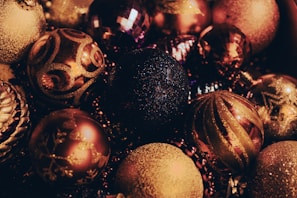 A collection of festive ornaments with intricate designs and glittery surfaces, showcasing a variety of spherical shapes and decorative patterns. The ornaments exhibit a rich blend of colors and shimmer, adding a touch of elegance.