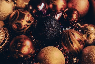 A collection of festive ornaments with intricate designs and glittery surfaces, showcasing a variety of spherical shapes and decorative patterns. The ornaments exhibit a rich blend of colors and shimmer, adding a touch of elegance.