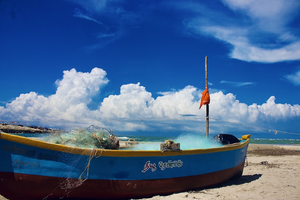 a blue and brown boat sitting on top of a sandy beach