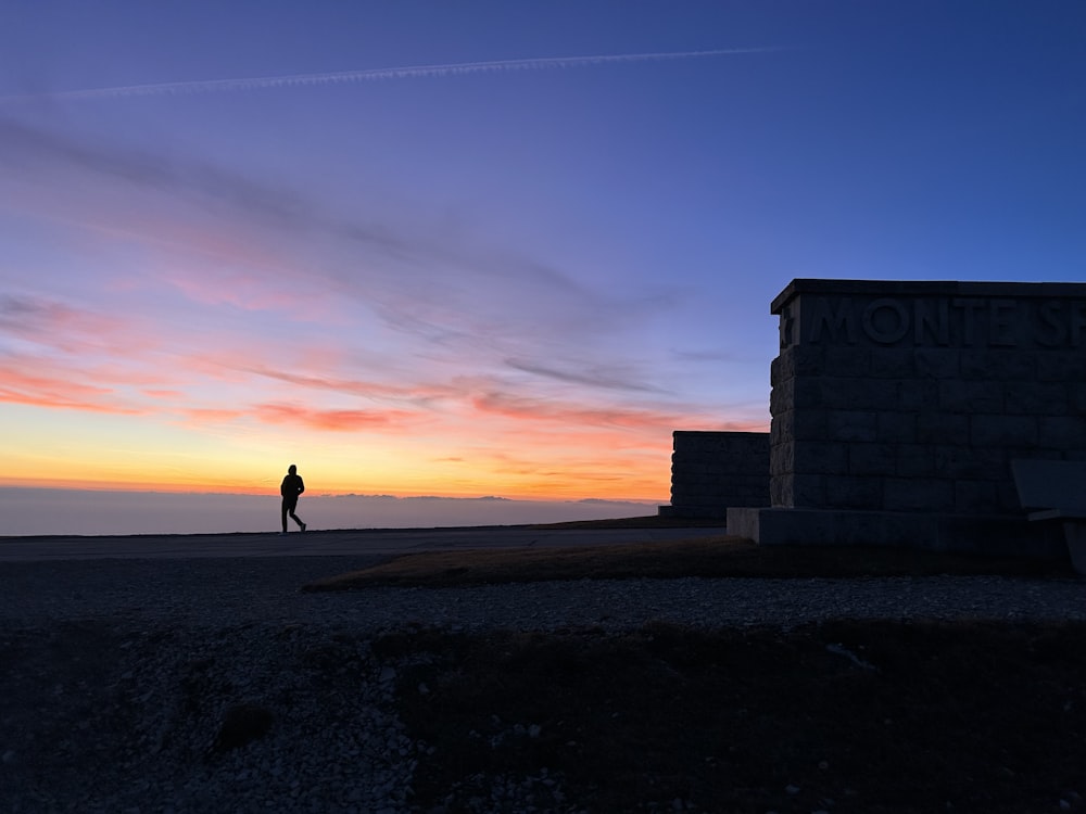 a person standing in front of a building at sunset