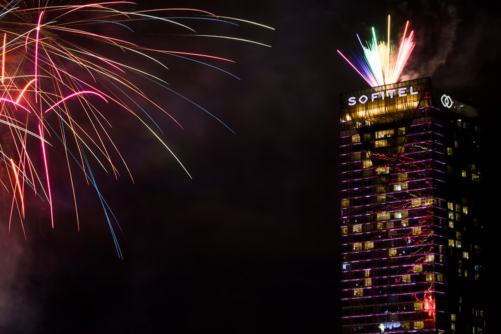 fireworks are lit up in the sky above a tall building