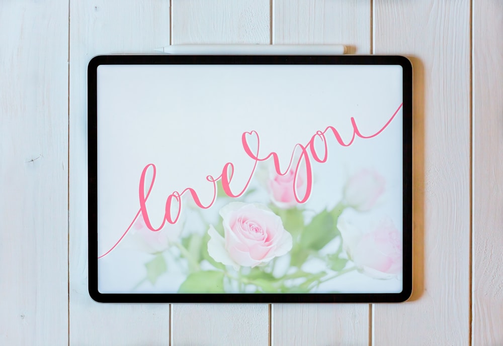 a picture of a pink rose with the word love spelled in cursive writing