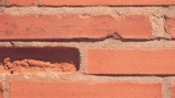 Close-up of a grimy brick wall restored to vibrant red.