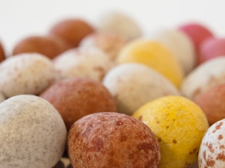 Close-up of a luxurious dark chocolate Easter egg with golden decorative accents on a cream background.