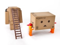 A series of baby versions interacting playfully around a large cardboard box setup.