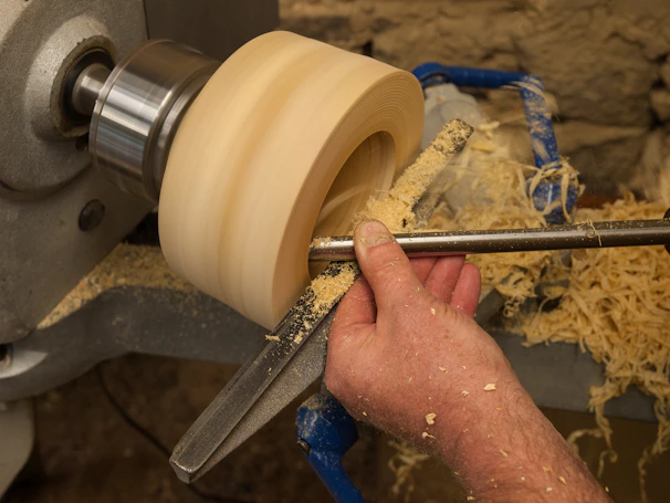 Artisan carefully shaping a wooden handle on a lathe in the workshop.
