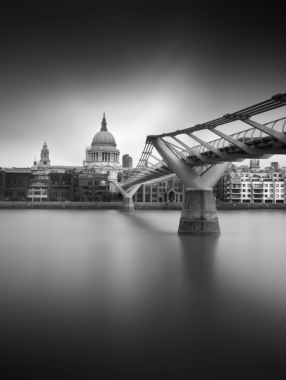 une photo en noir et blanc d’un pont au-dessus de l’eau