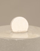 A premium recovery device resting on a warm sand-colored surface, bathed in natural light.