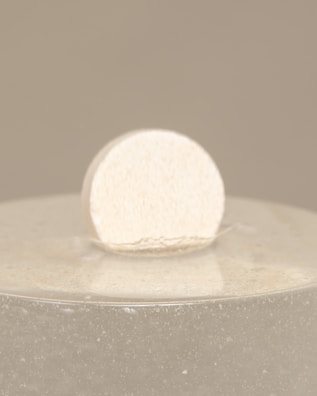 A premium recovery device resting on a warm sand-colored surface, bathed in natural light.