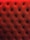 A close-up of a tufted, padded surface with a luxurious texture. The material is upholstered in a deep red color, and small buttons create a diamond pattern.